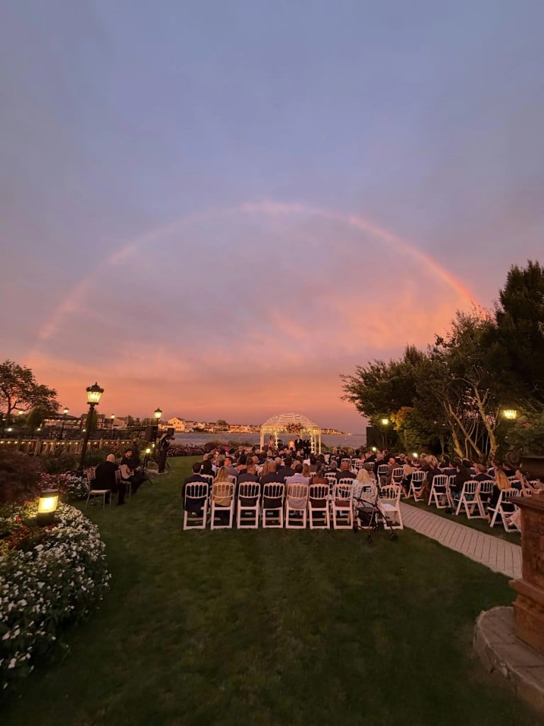 Outdoor wedding ceremony at sunset under a rainbow at Riviera Waterfront Mansion