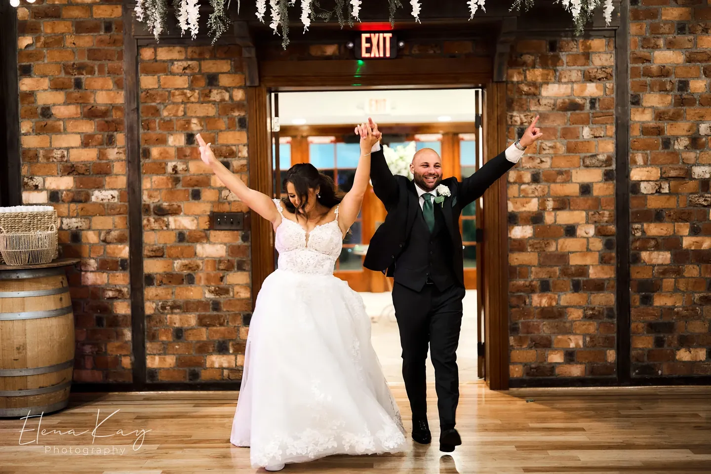 Bride and groom celebrating as they come through the brick entrance by Elena Kay Photography