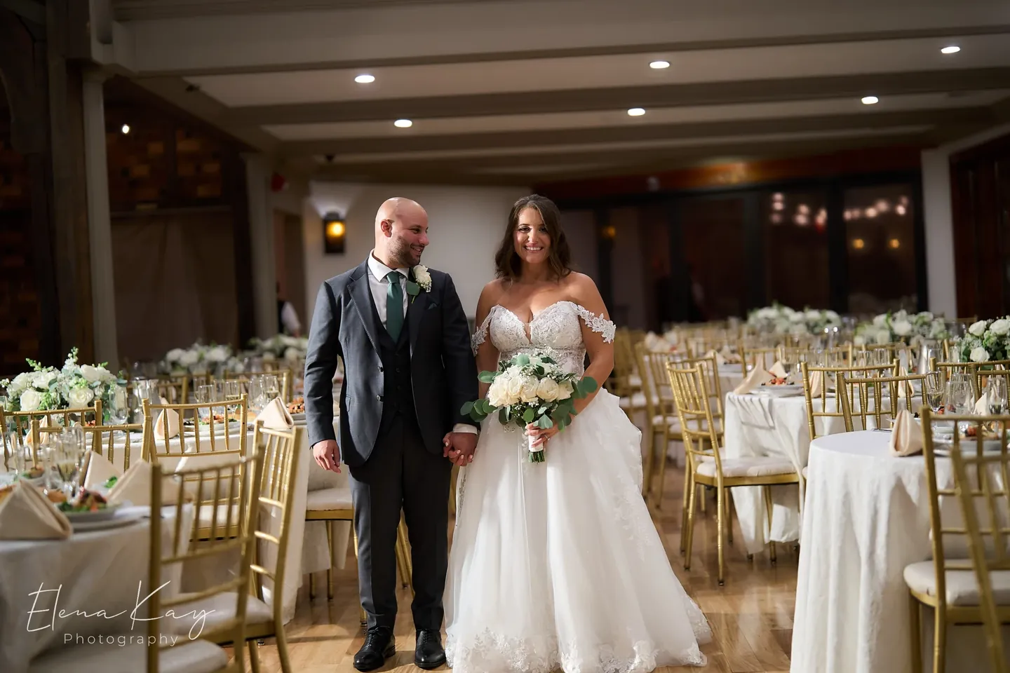 Bride and groom walking through the ballroom set for the reception by Elena Kay Photography