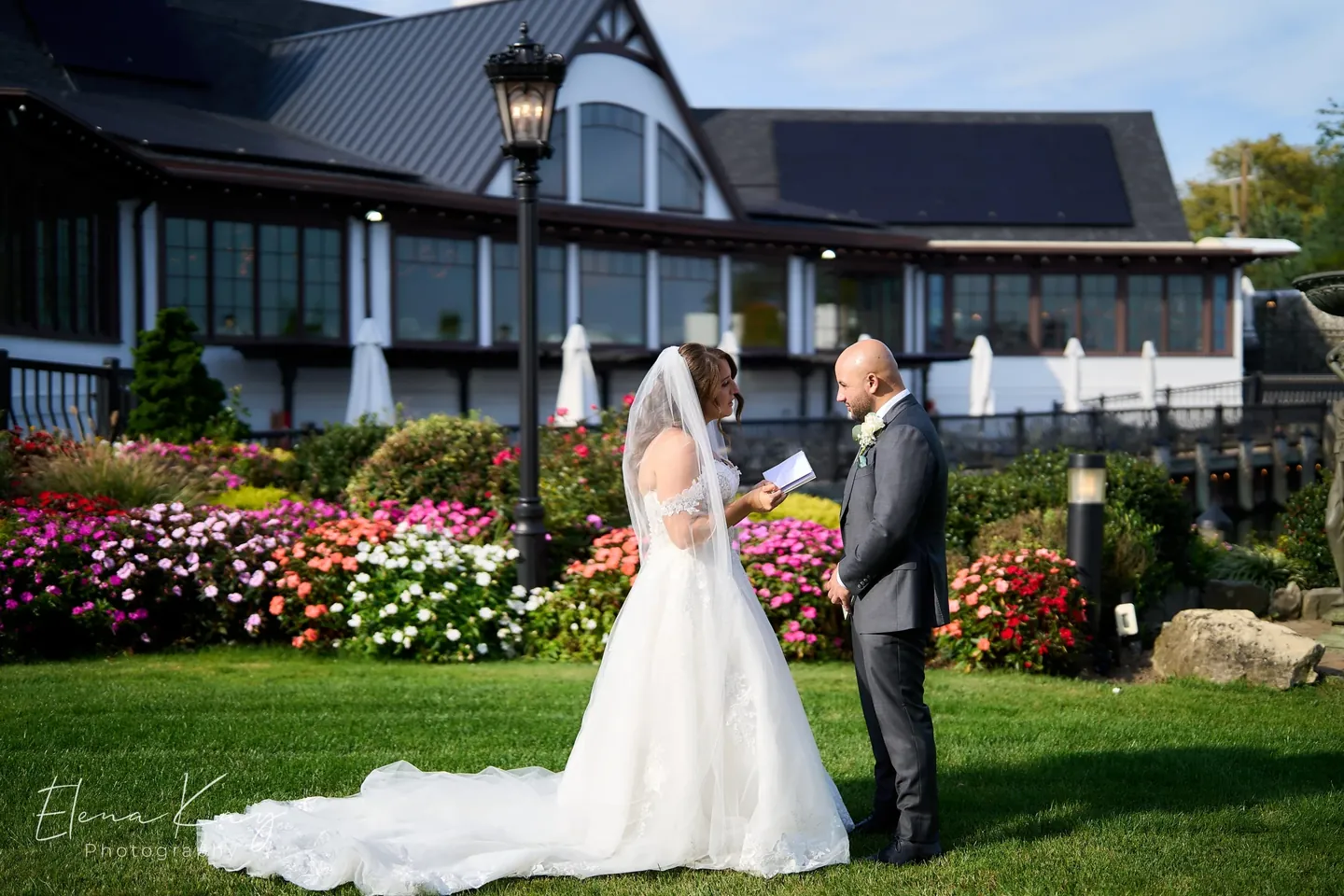 Bride reading her vows to the groom on the lawn in front of the mansion by Elena Kay Photography