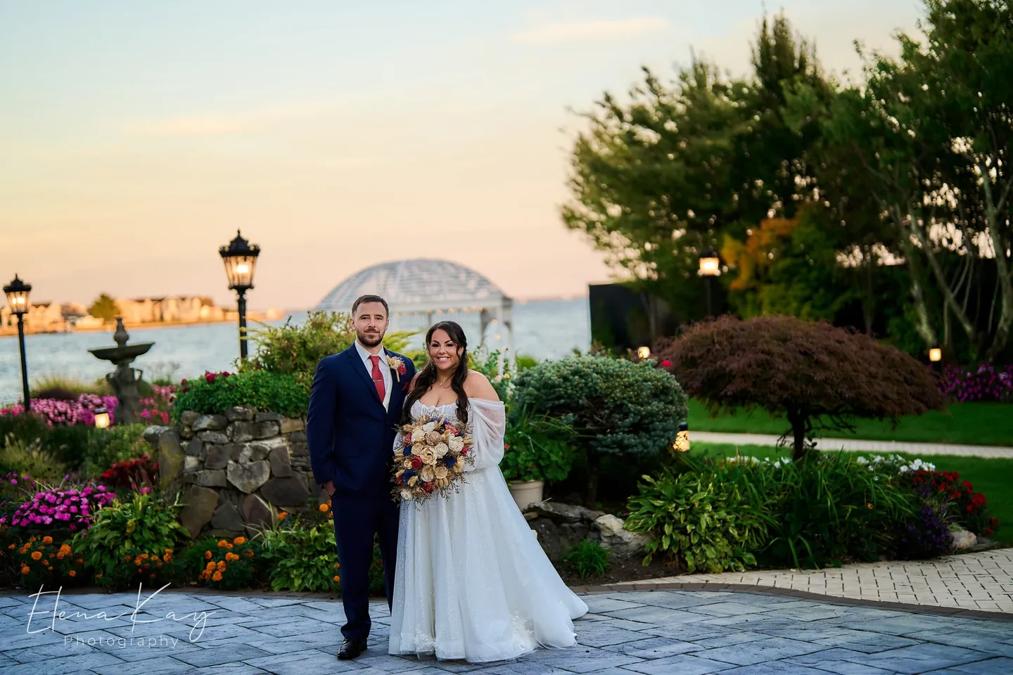 Bride and groom at sunset in the waterfront gardens with the gazebo and bay behind them by Elena Kay Photography